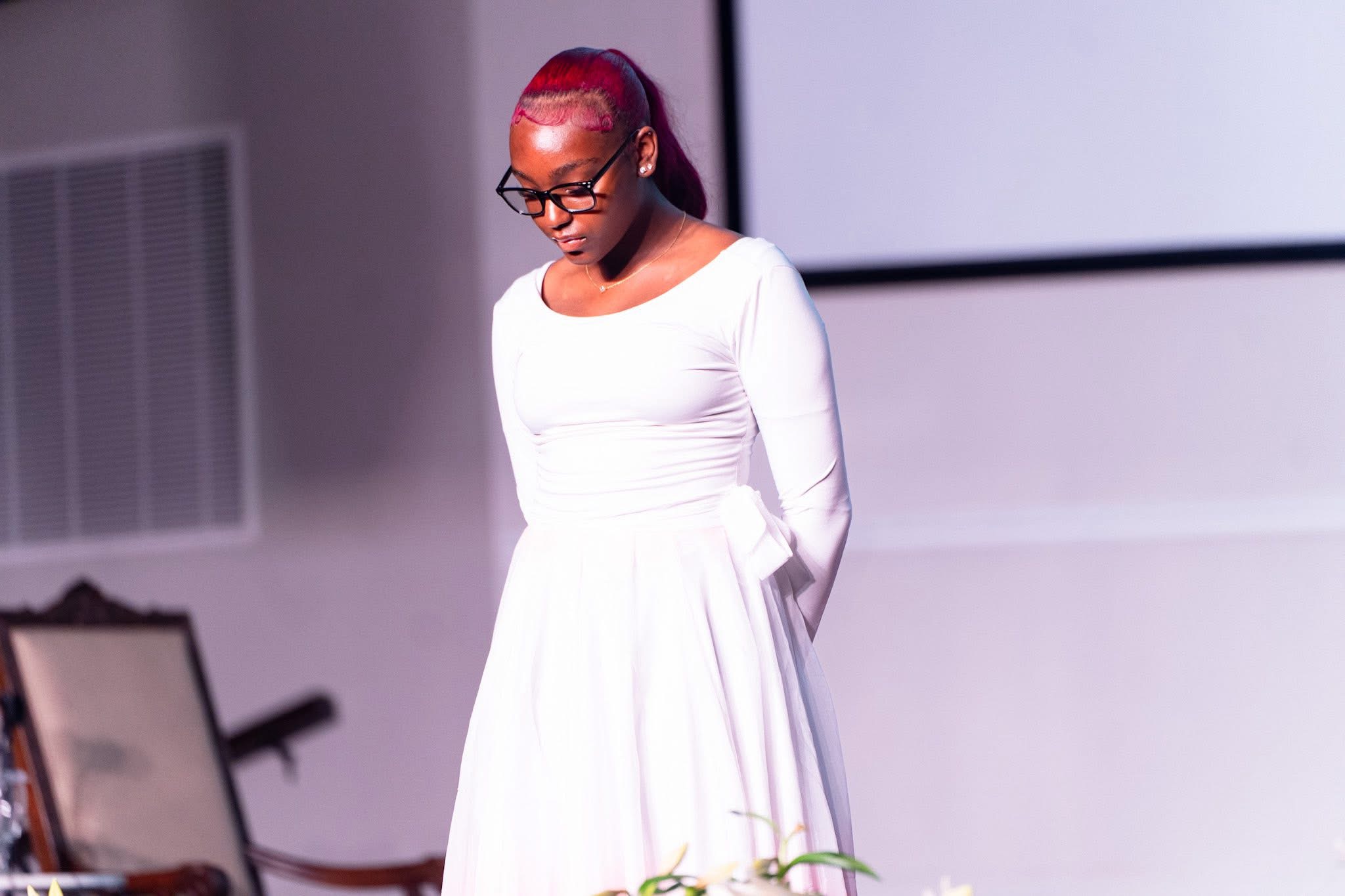 Kadence in a white gown during a formal program moment